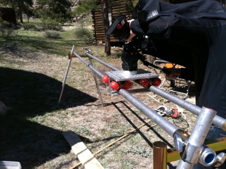 Camera mounted on a custom slider rig supported by grip equipment on an outdoor mountain location